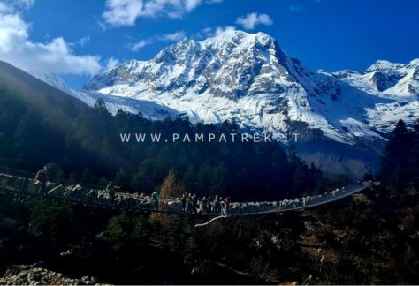 Escursionisti attraversano un ponte sospeso durante il trekking del Circuito del Manaslu