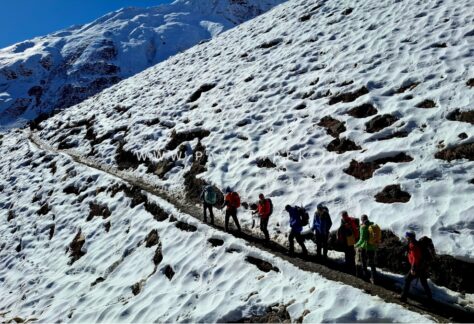 Escursionisti percorrono un sentiero innevato durante l’avvicinamento al Larkya La