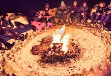 Gruppo riunito attorno al falò durante un'esperienza sulla neve a Salla